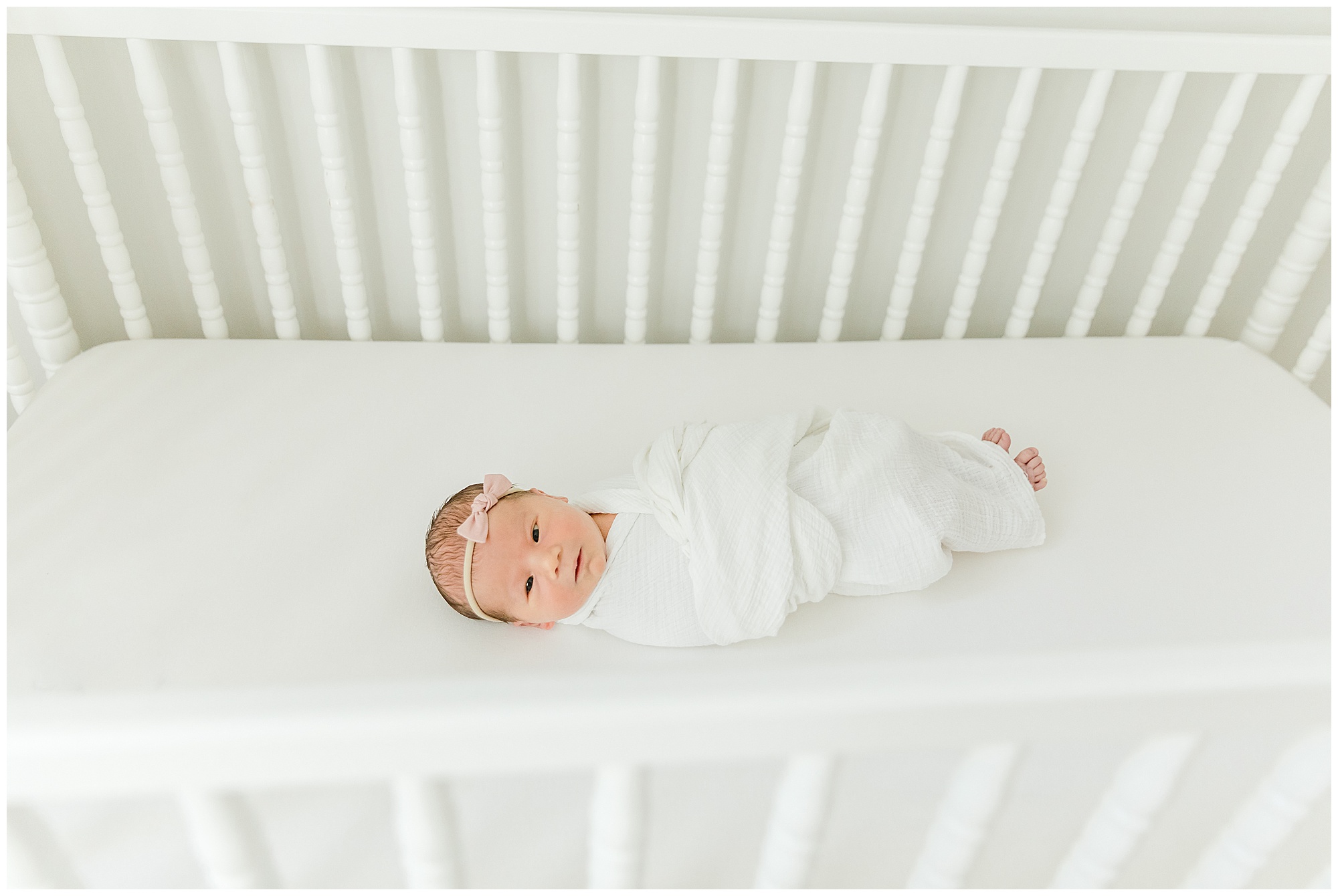 Portrait of baby in a white crib by Greenville SC photographers Molly Hensley.