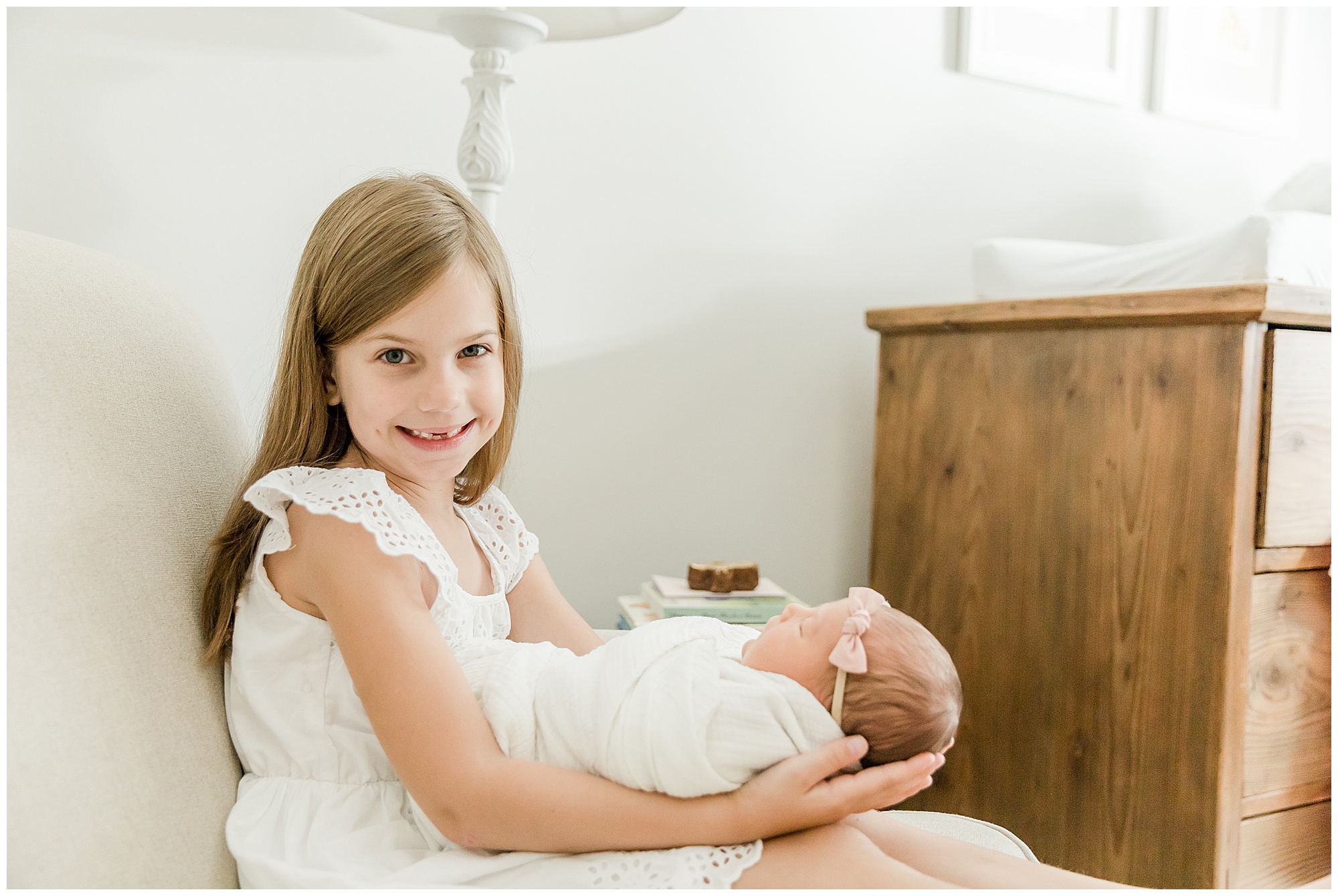 Young girl holding her baby sister for a newborn portrait