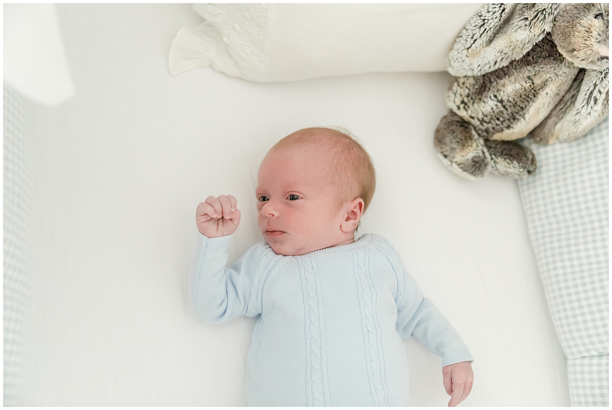 Classic photo of a newborn in blue knit sweater in his crib by Greenville photographer