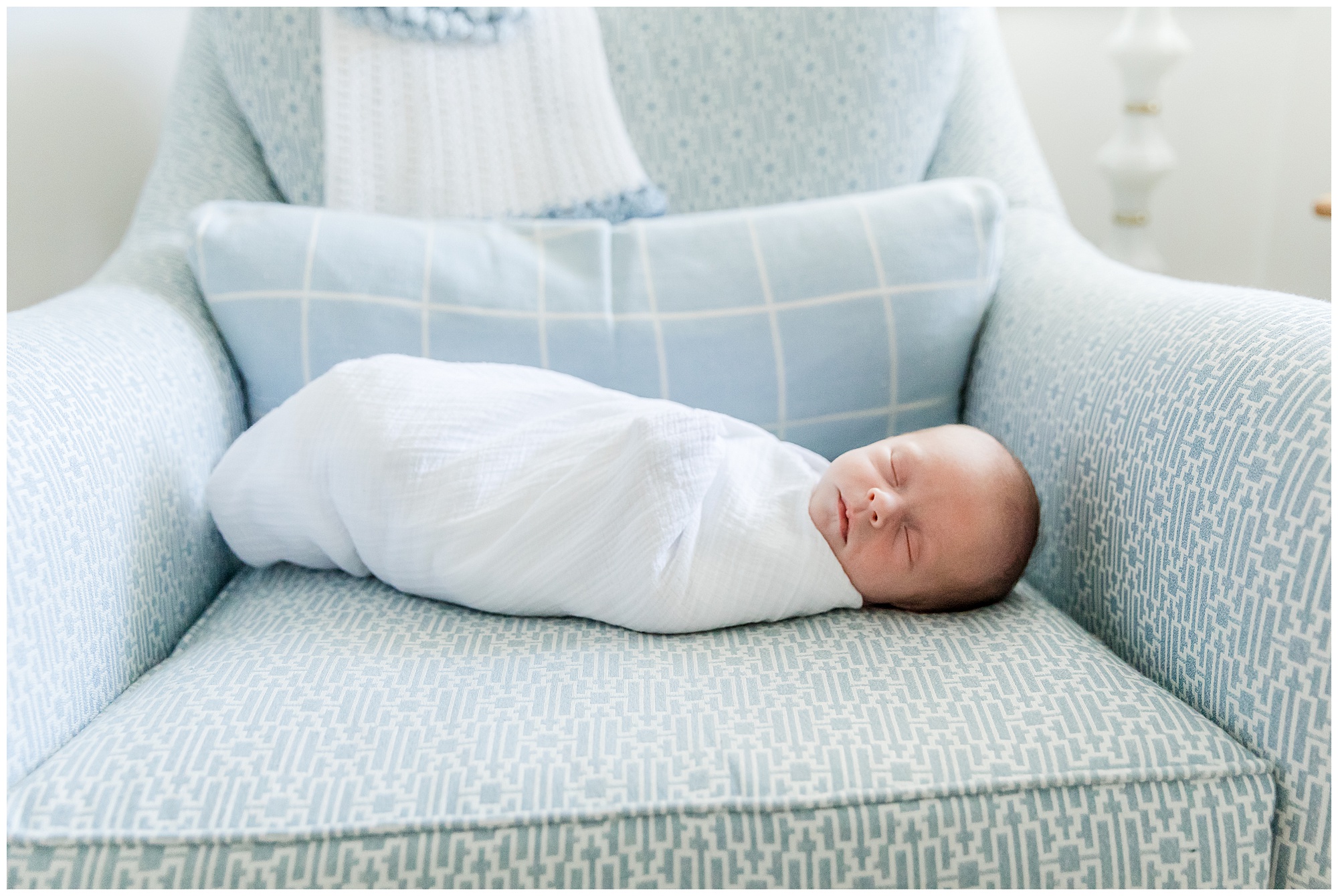 Portrait of swaddled baby on a blue patterned chare