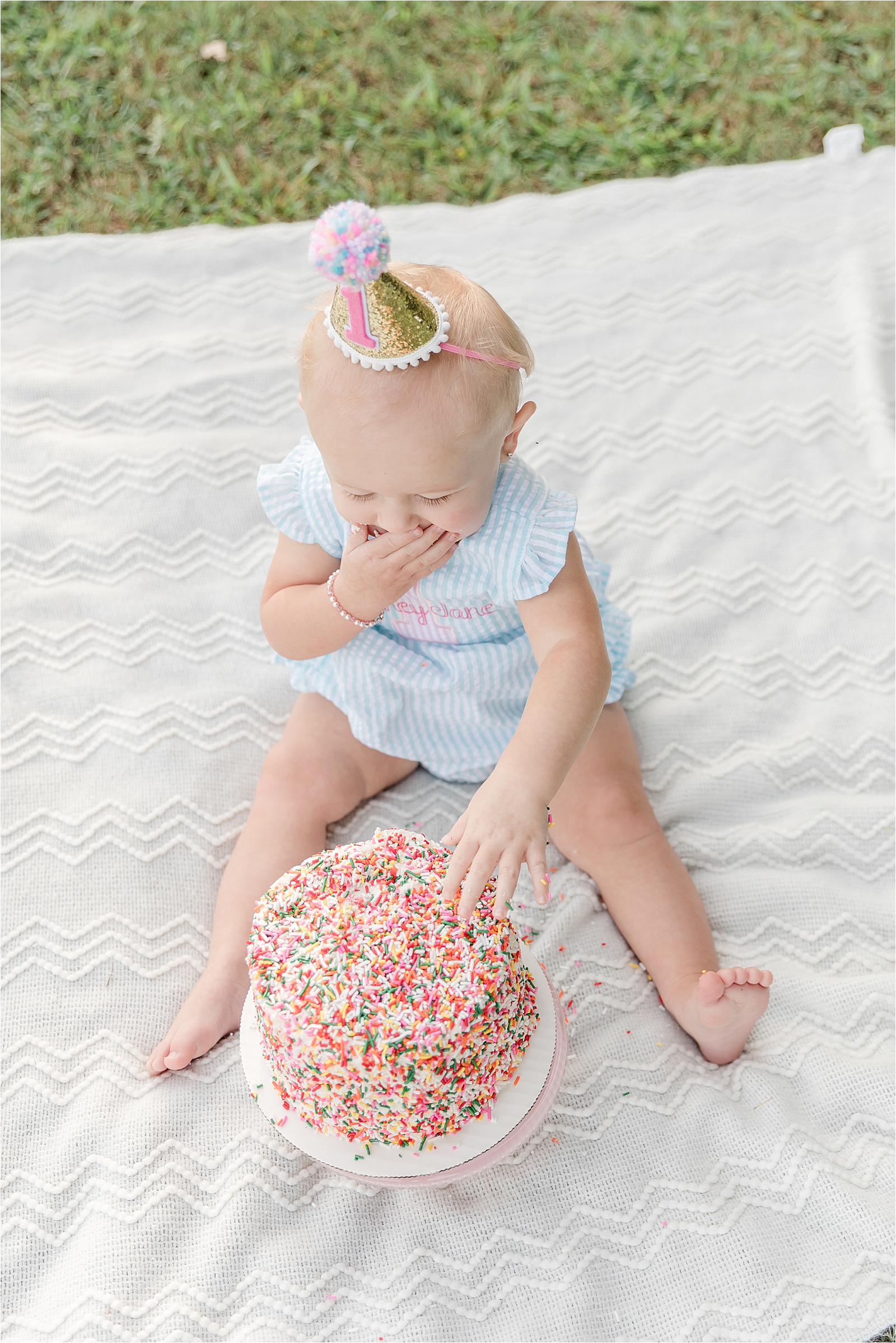 Baby girl with sequin party hat eating a sprinkle cake by photographer in Greenville SC