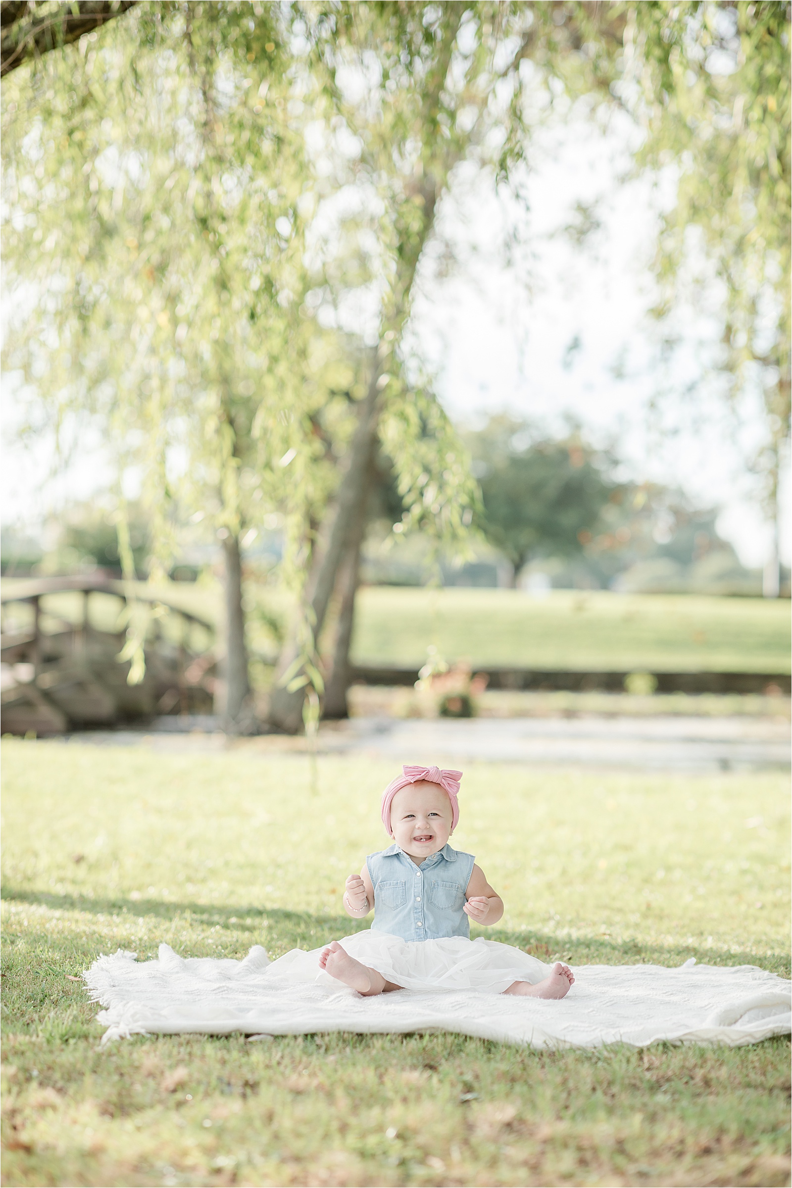 Portrait of baby sitting on white blanket by photographer in Greenville SC