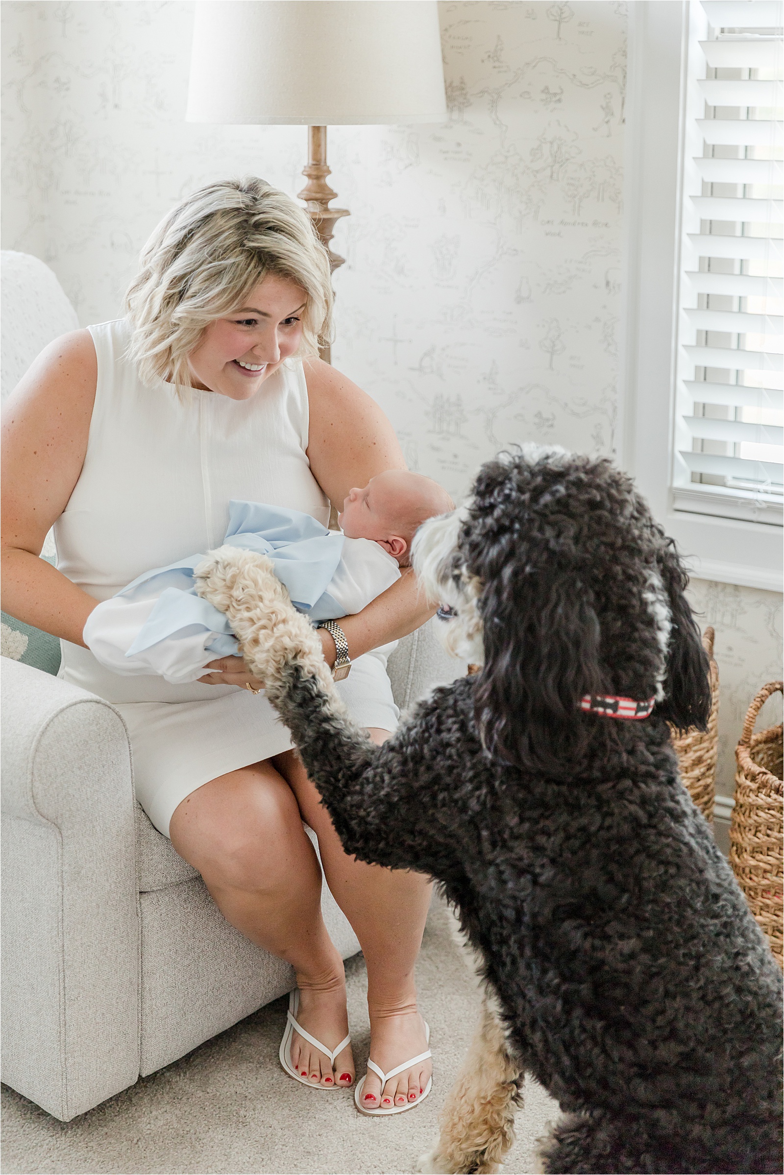 Mom holding newborn son as dog rests his paw on baby