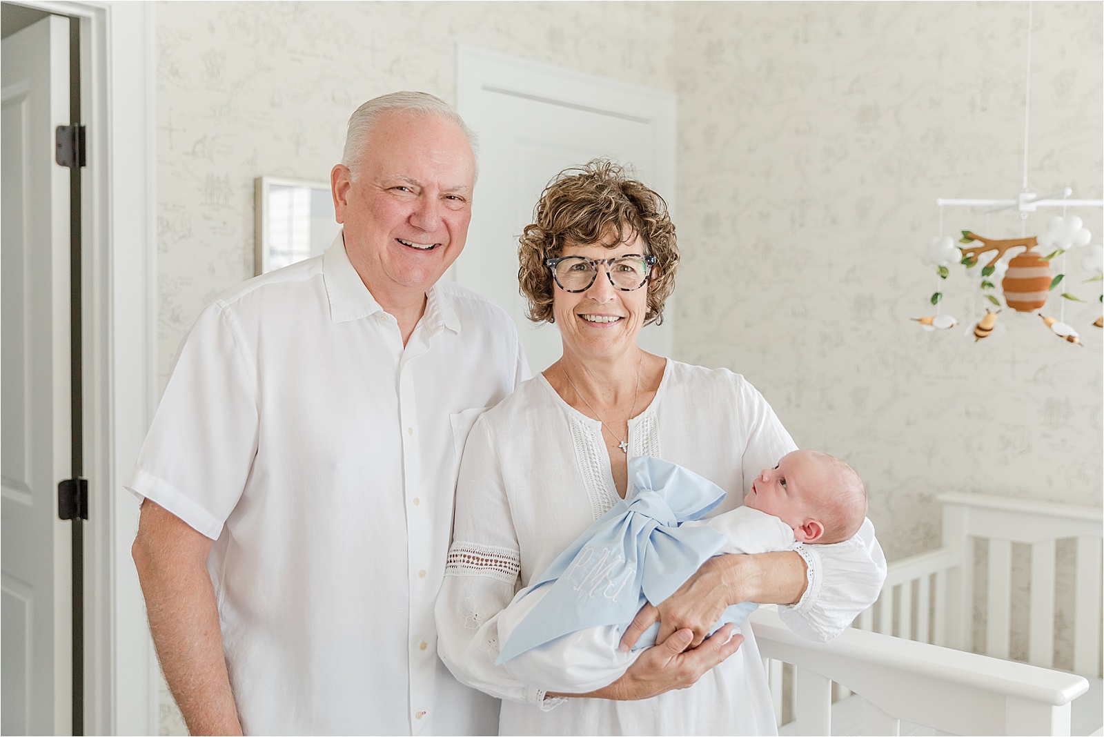 Newborn in arms of his grandparents in Winnie the Pooh Nursery
