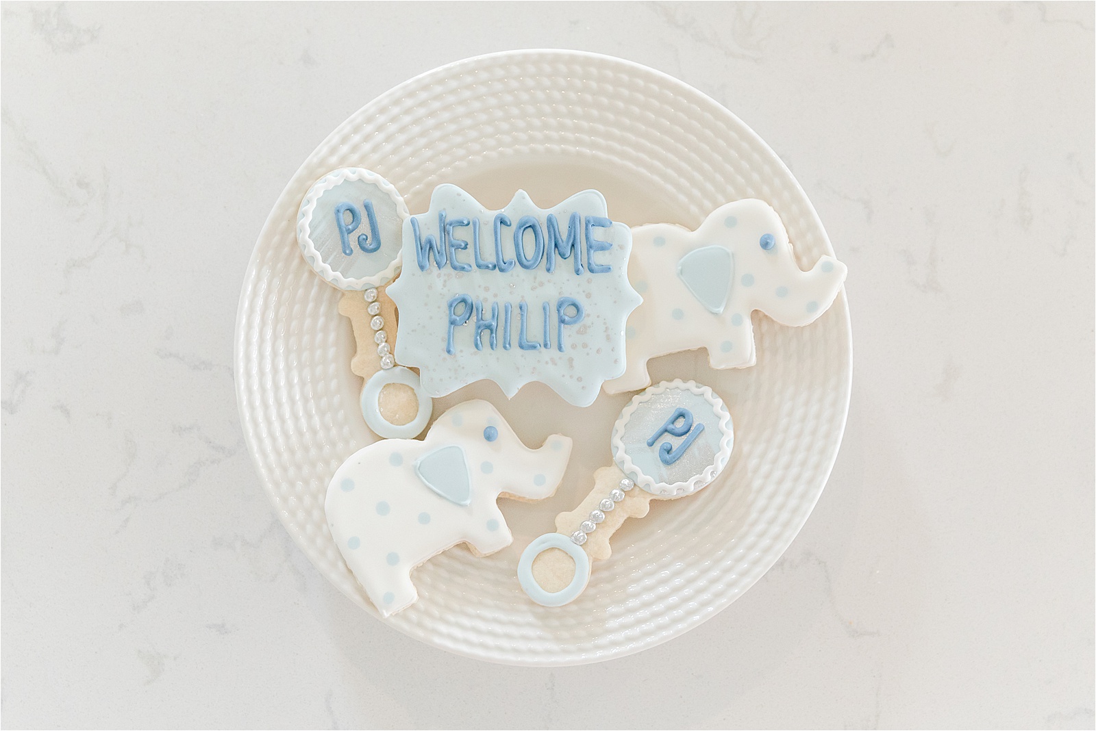 Custom made cookies in the shape of a rattle, elephant, and name plaque for newborn baby boy