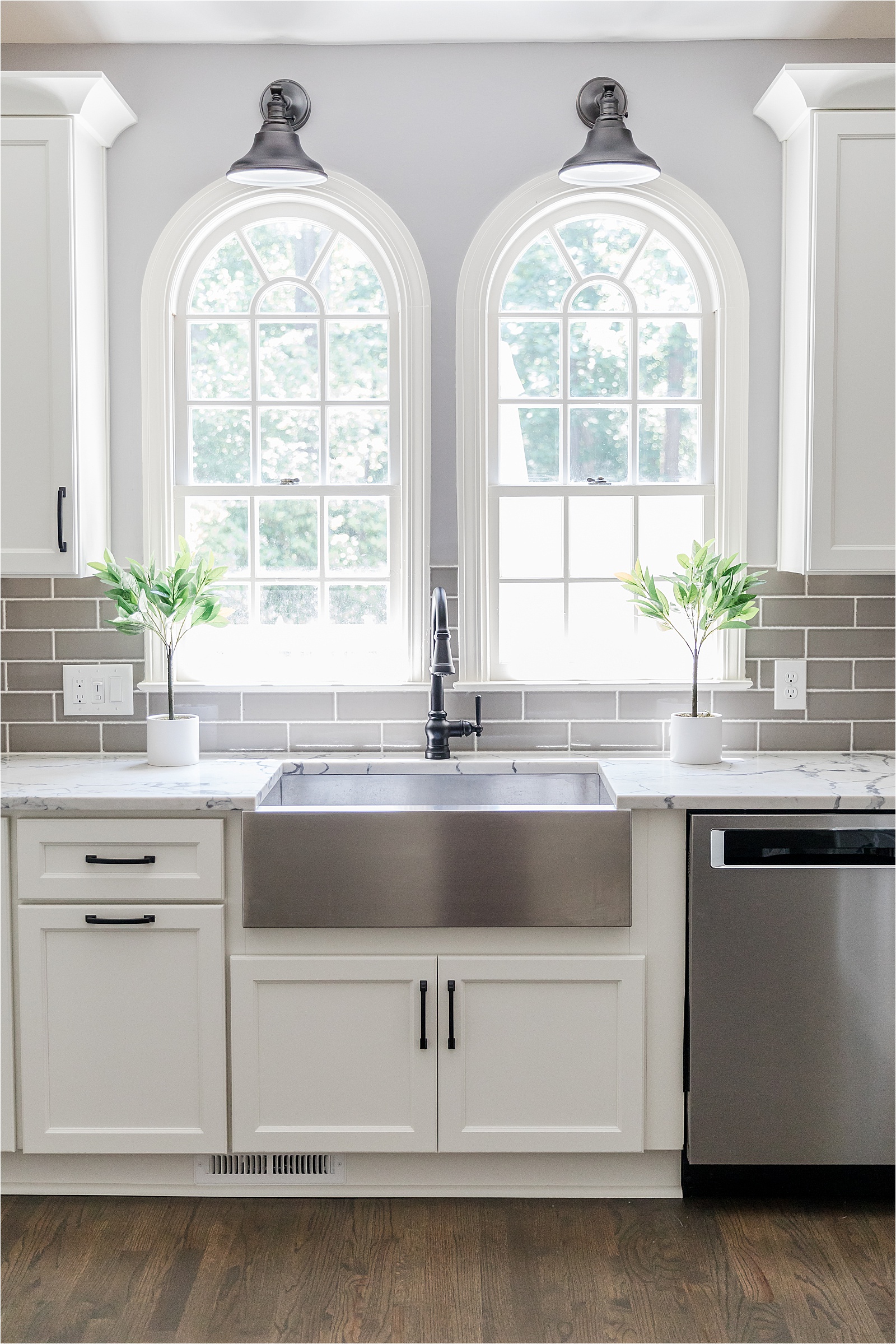 two arched windows above stainless steel farm sink