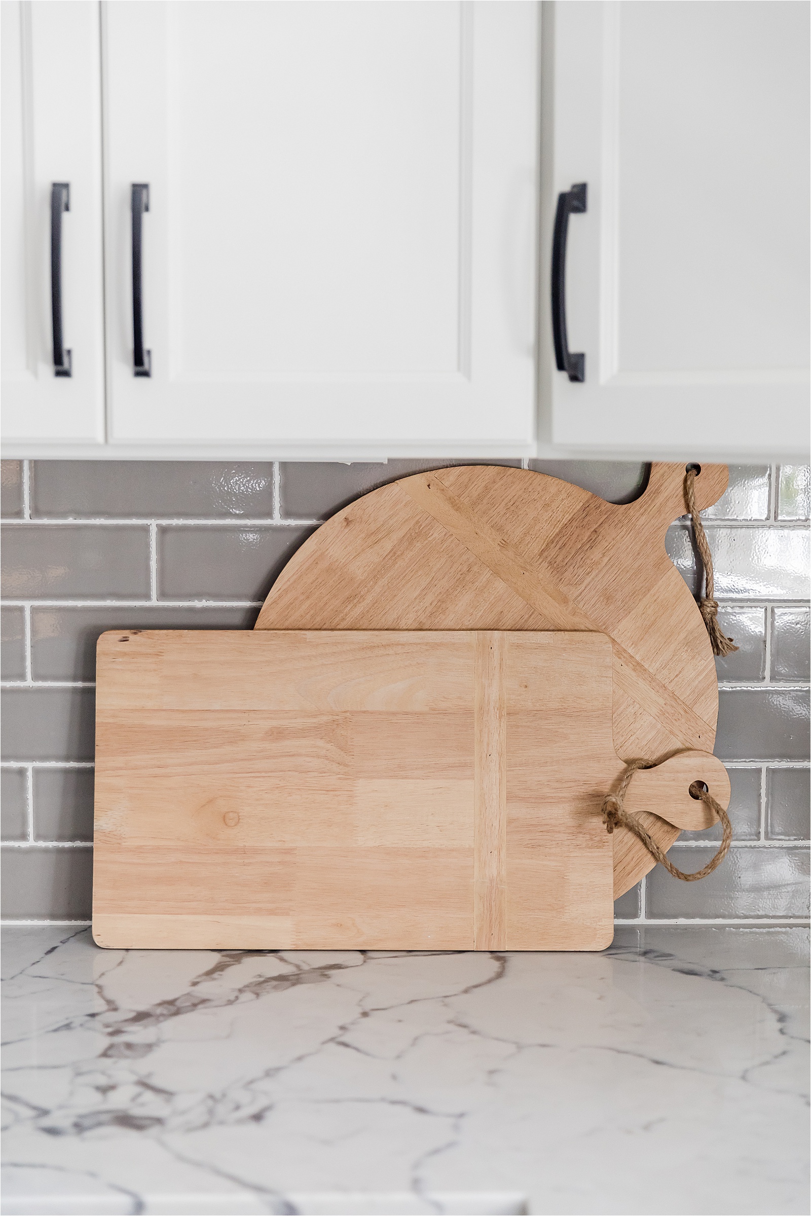 two cutting boards in front of grey subway tile backsplash