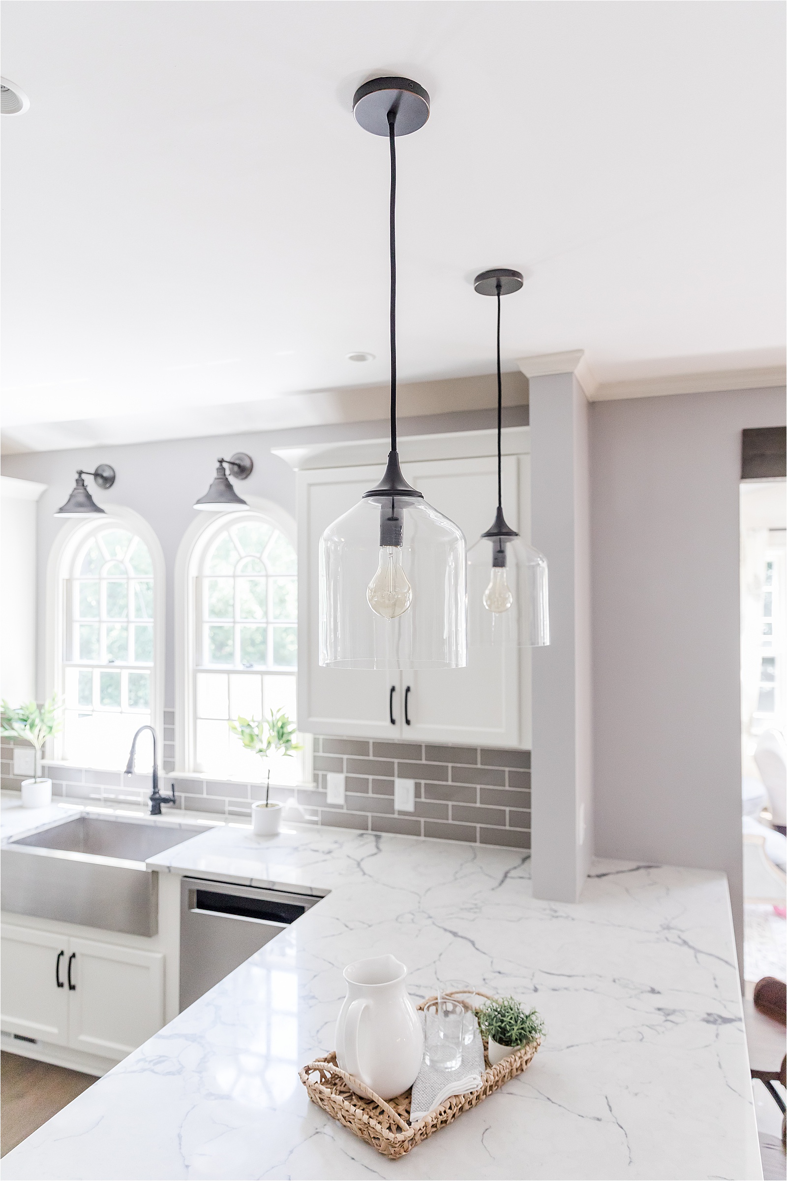 Glass pendant lights about white peninsula in kitchen