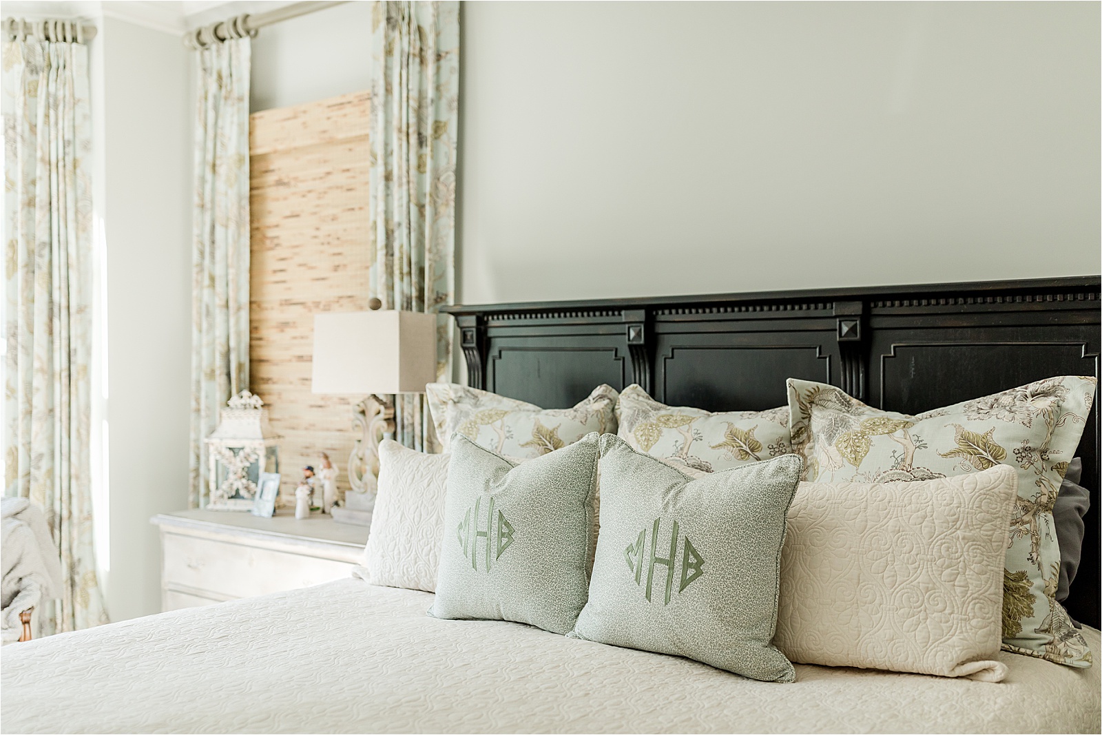 Pale green and tan master bedroom with monogrammed pillow and floral pattern accents