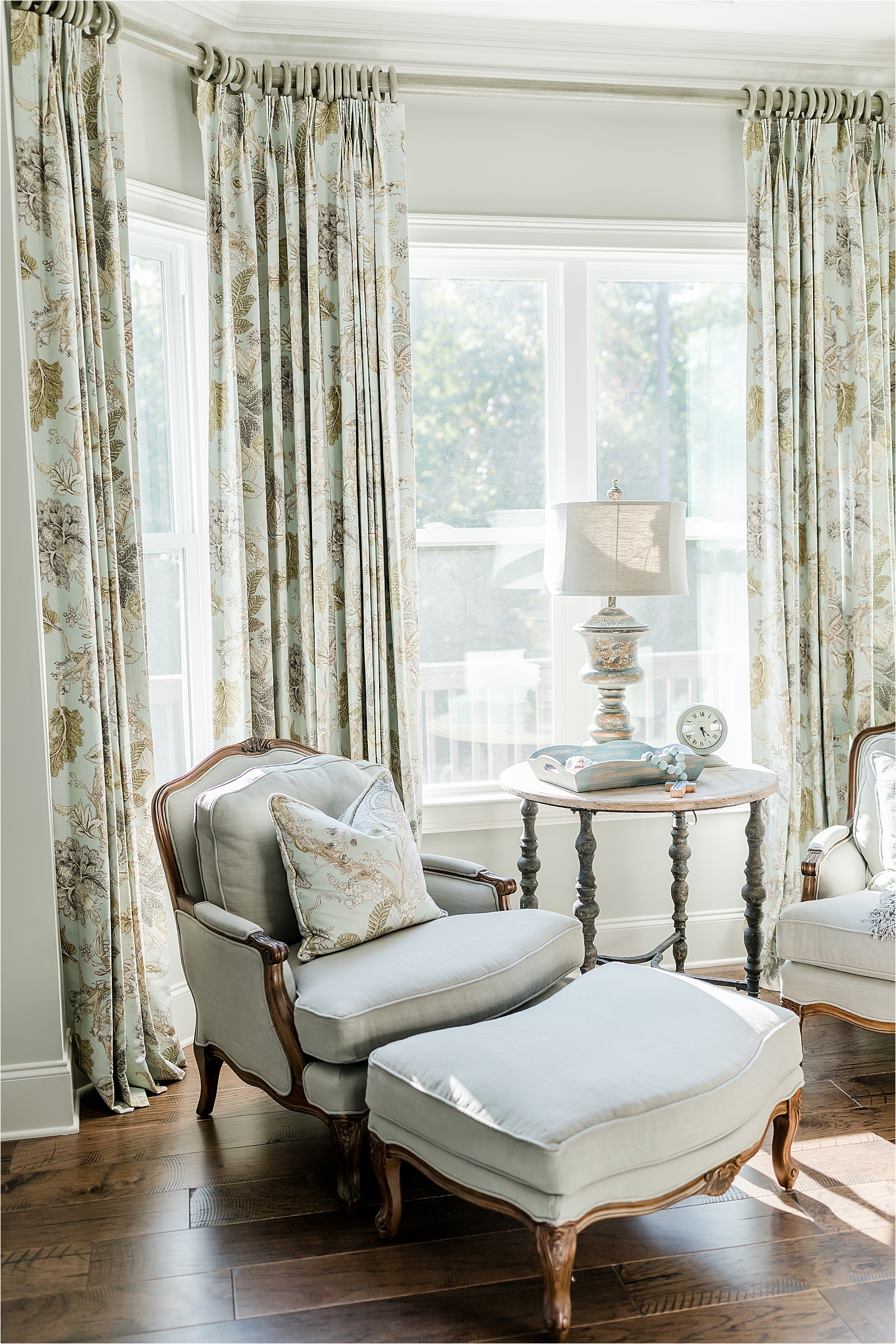 Chair and ottoman in from of large windows in a traditional master bedroom