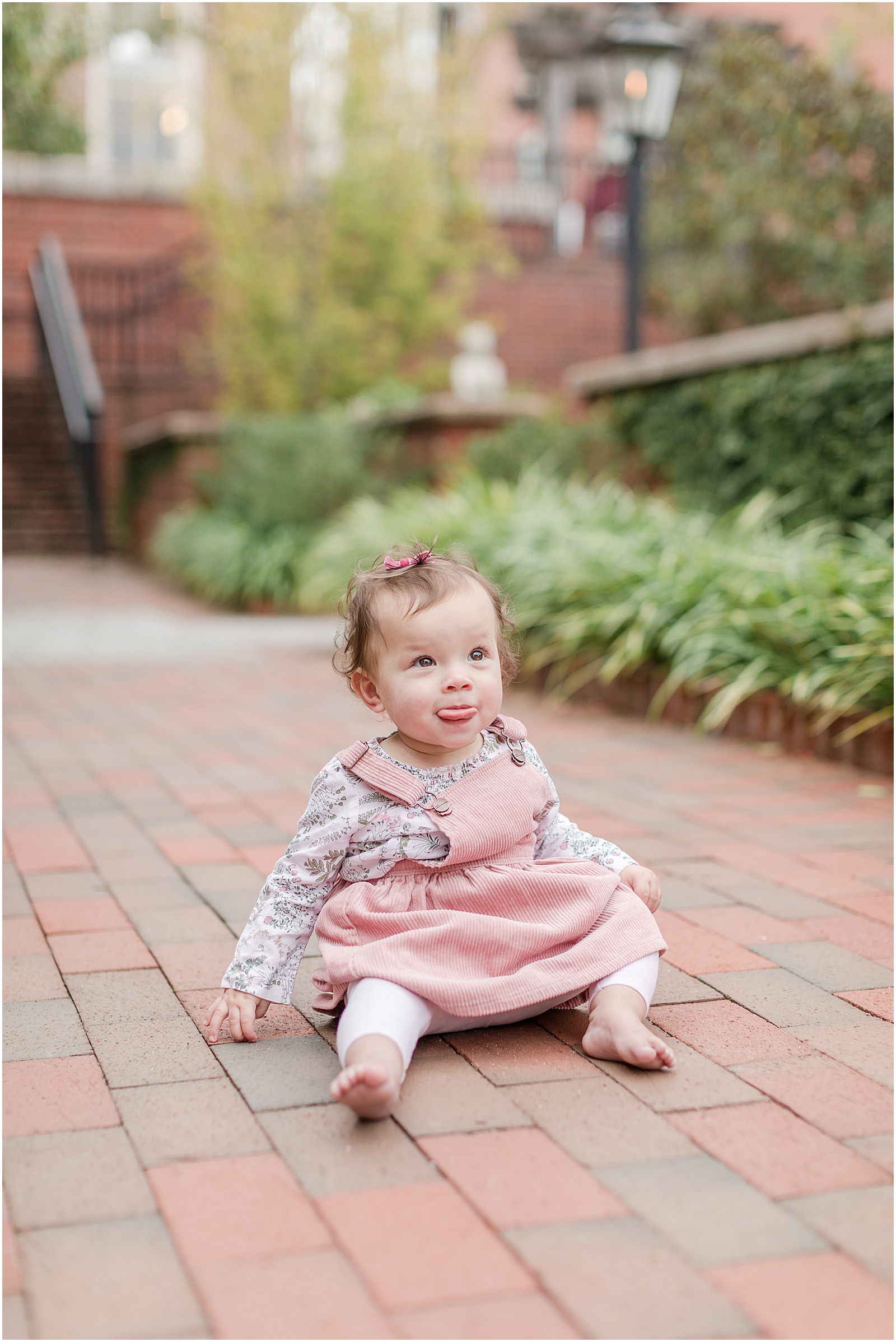 One year old girl sitting on brick pathway in Alpharetta