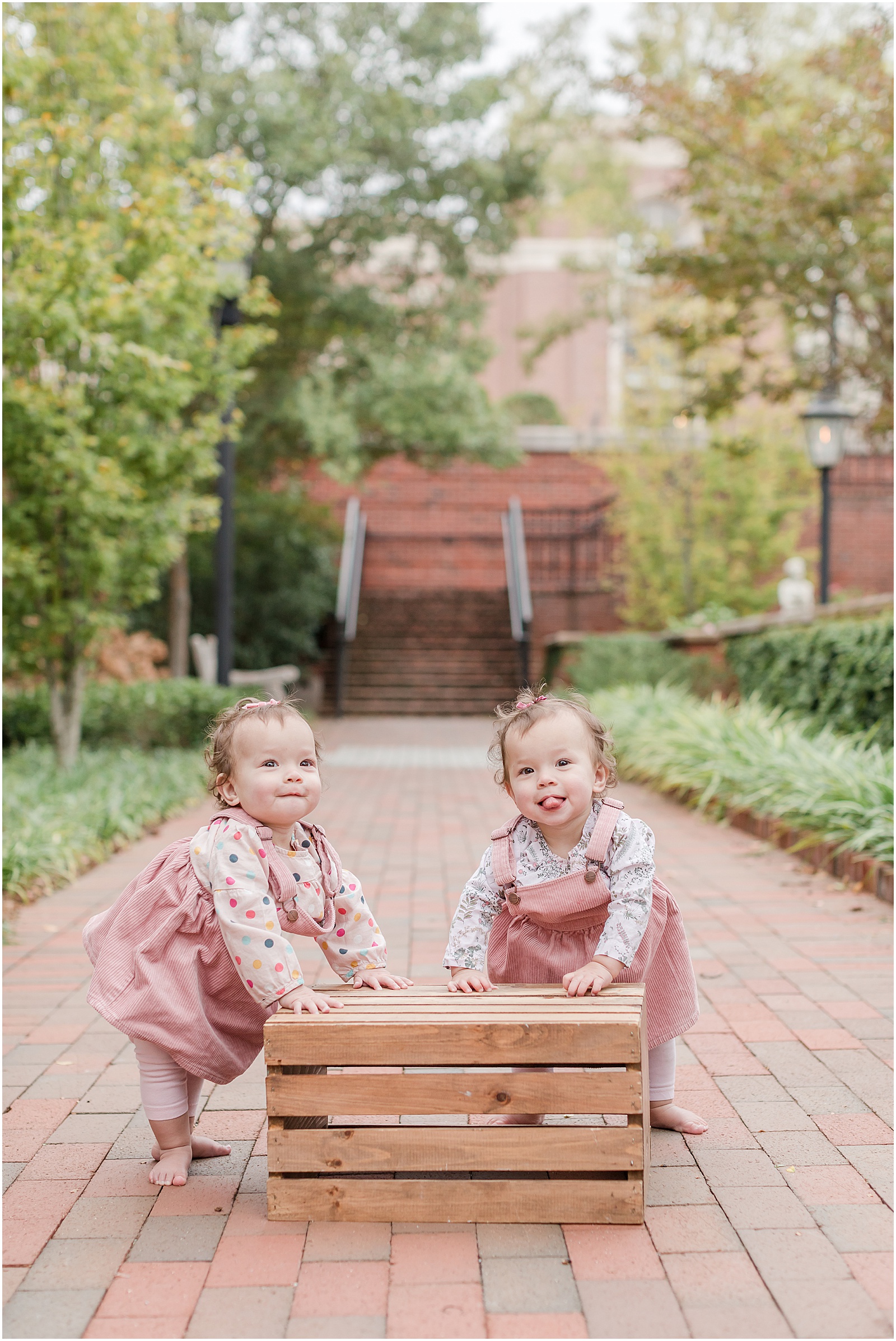 Twin one year olds posing for a photo on a brick pathway