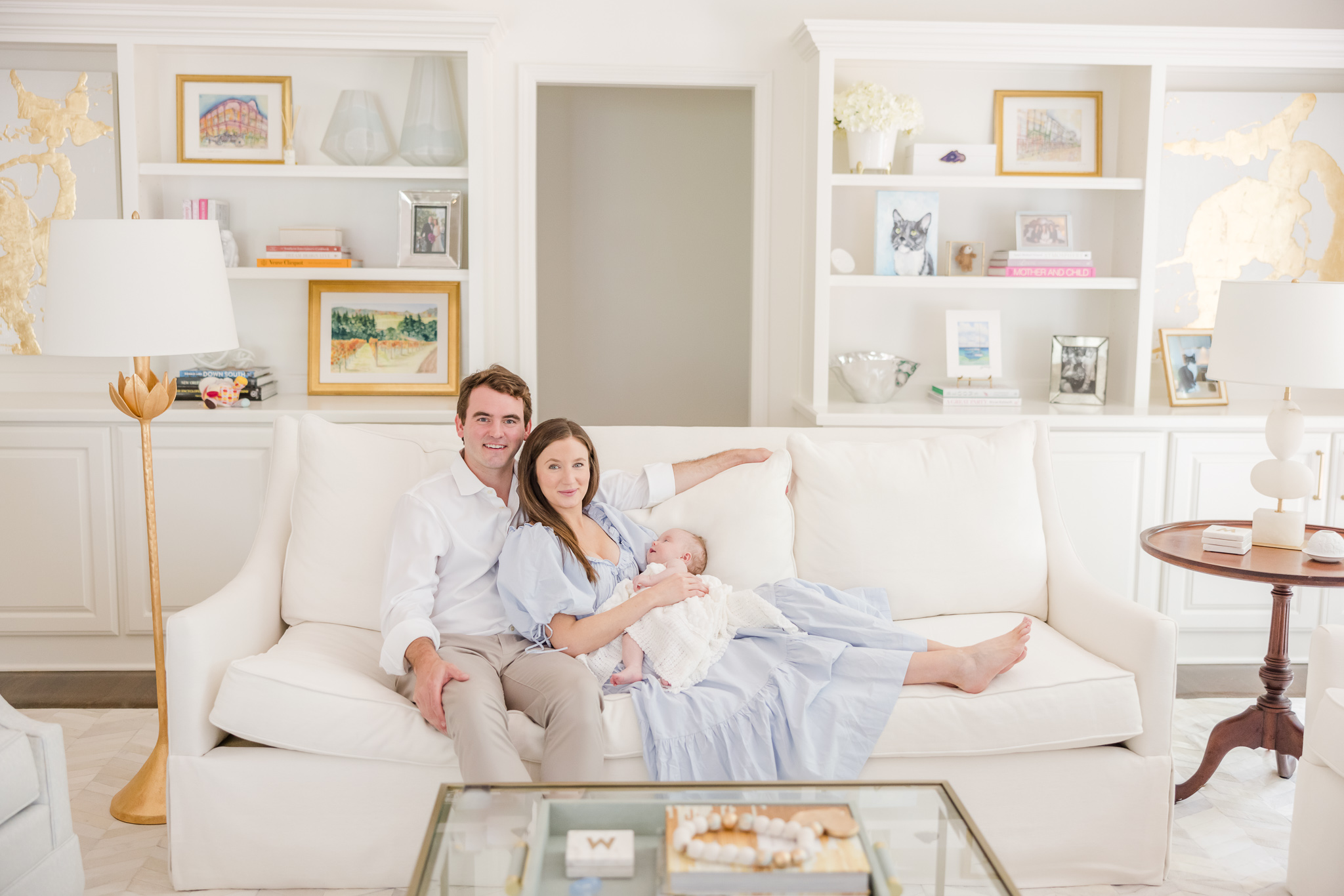 parents holding newborn on a white couch