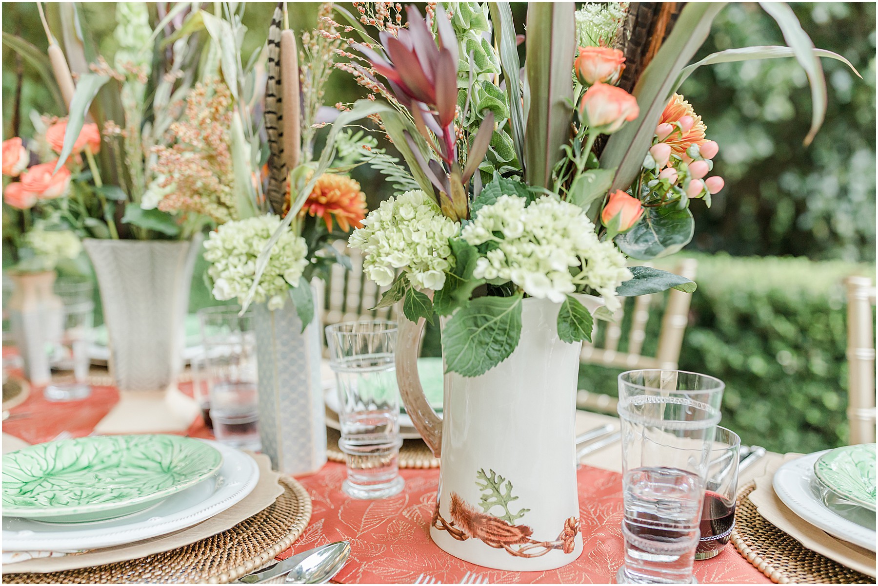 A close up of a vase and flowers on a fall inspired table setting.