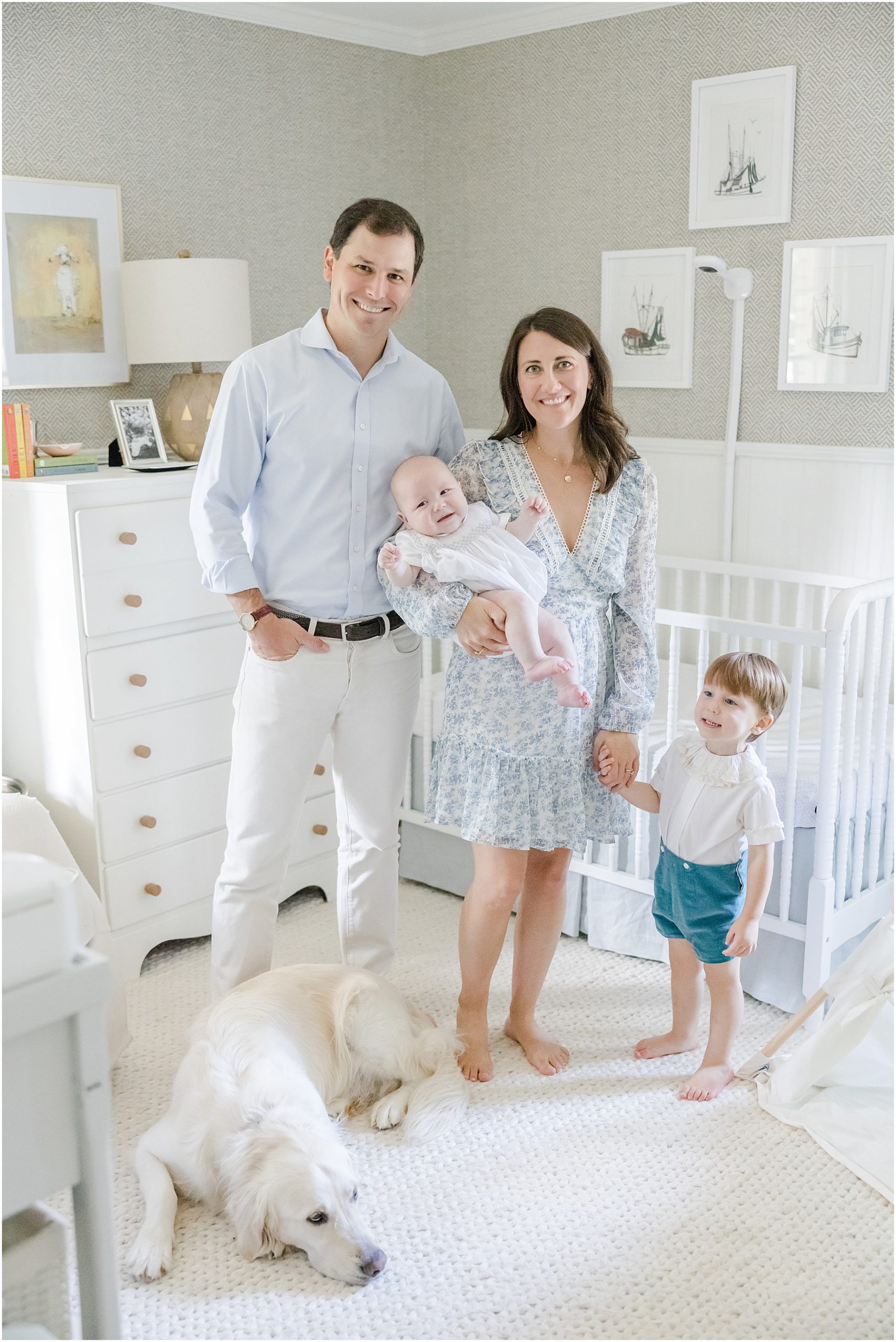 Portrait of a family in a nursery with wallpaper and framed boats 