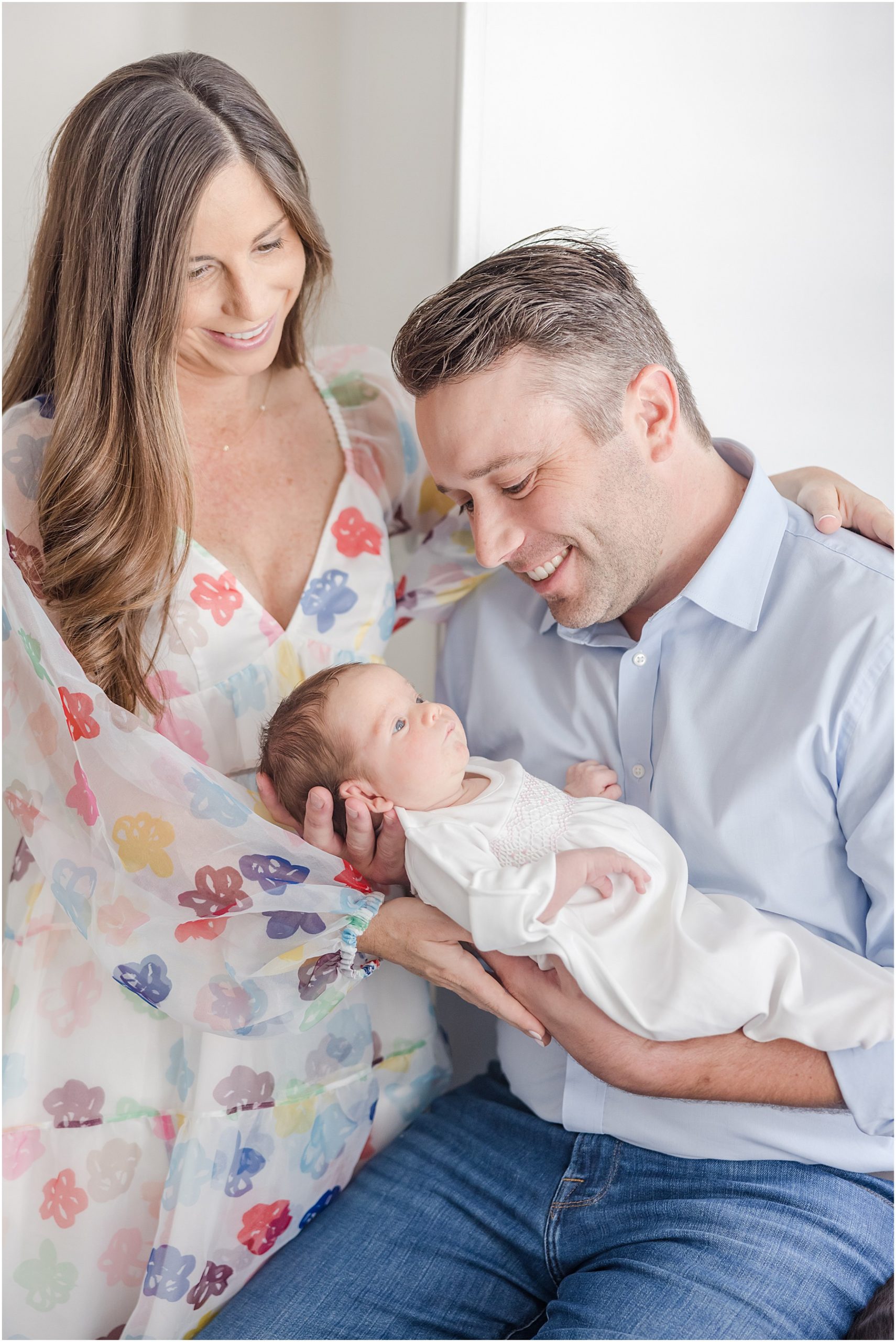 New parents smiling down at their baby girl for their in home Greenville newborn session.