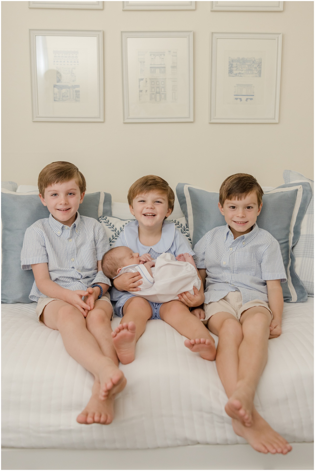 Greenville Newborn Photography of three young brothers smiling and holding their newborn baby brother.