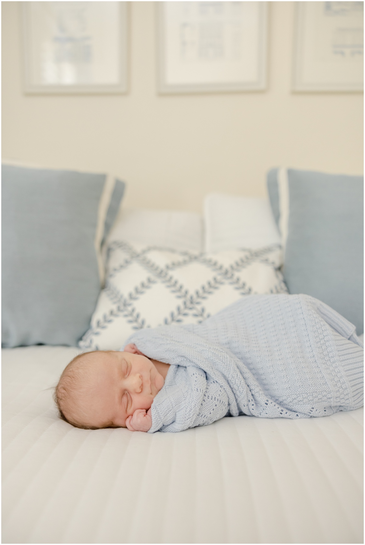Greenville Newborn Photography if a baby boy in  blue blanket sleeping on a white bed.