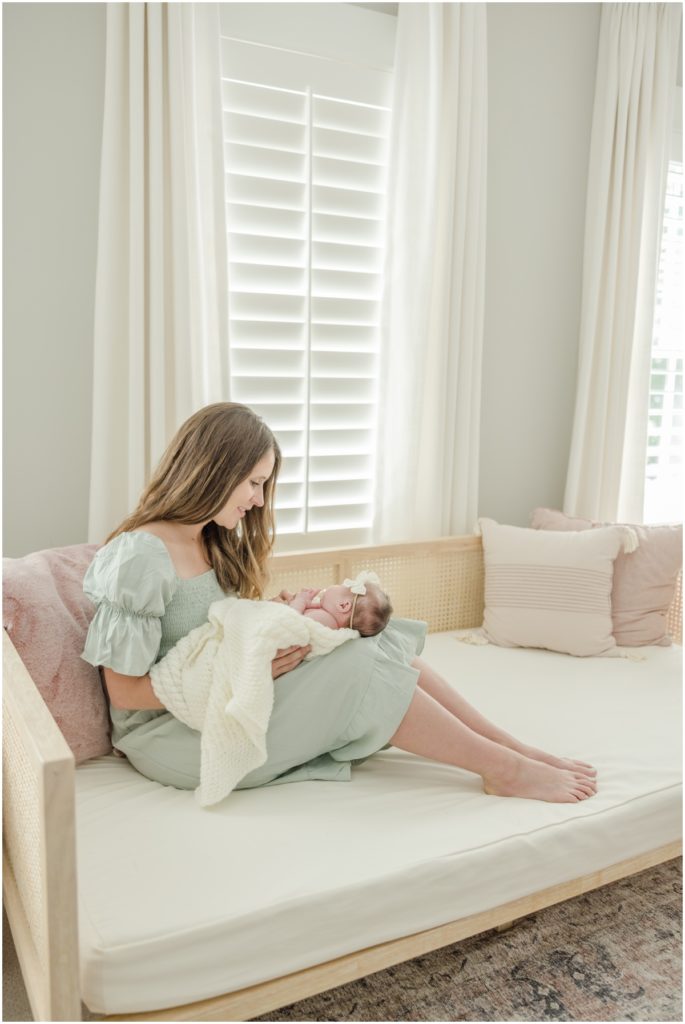 Portrait of a mother seated on a daybed gazing at her newborn daughter by Greenville photographer Molly Hensley.