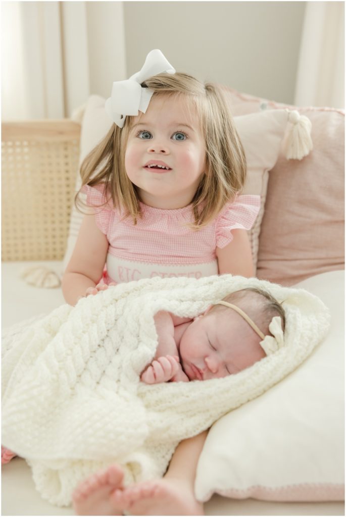 Portrait of toddler holding her newborn sister by Greenville photographer.