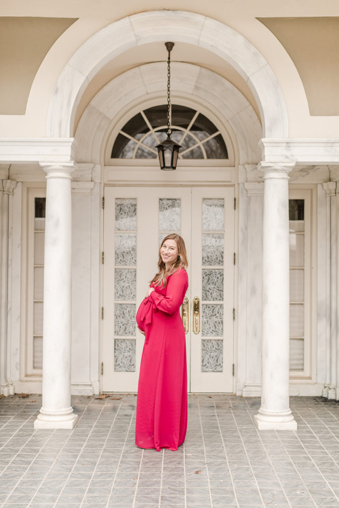 Expecting Mother smiling for a portrait while holding her belly by Greenville Maternity Photographer