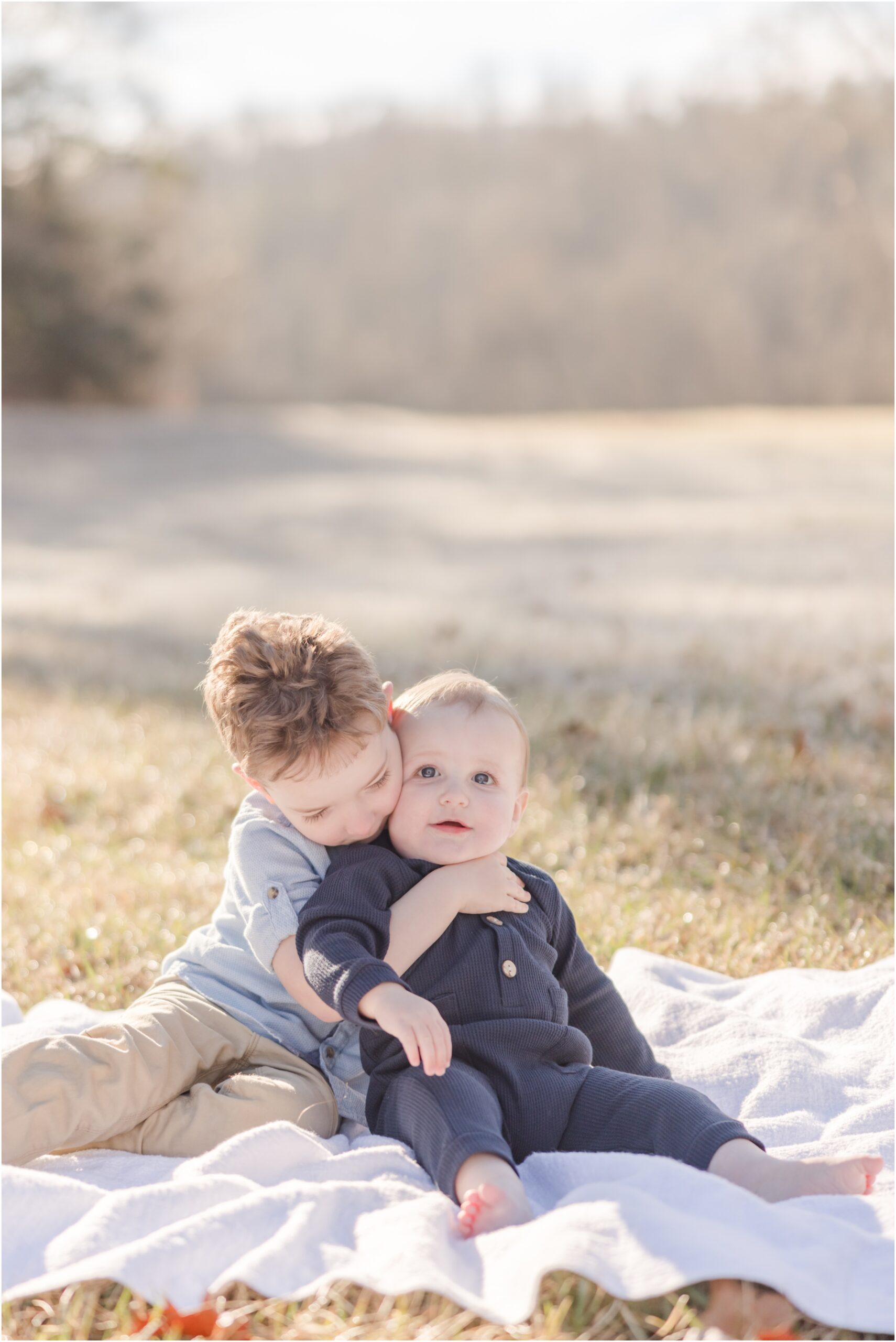 An older brother snuggles his baby brother while posing for Greenville photographer.