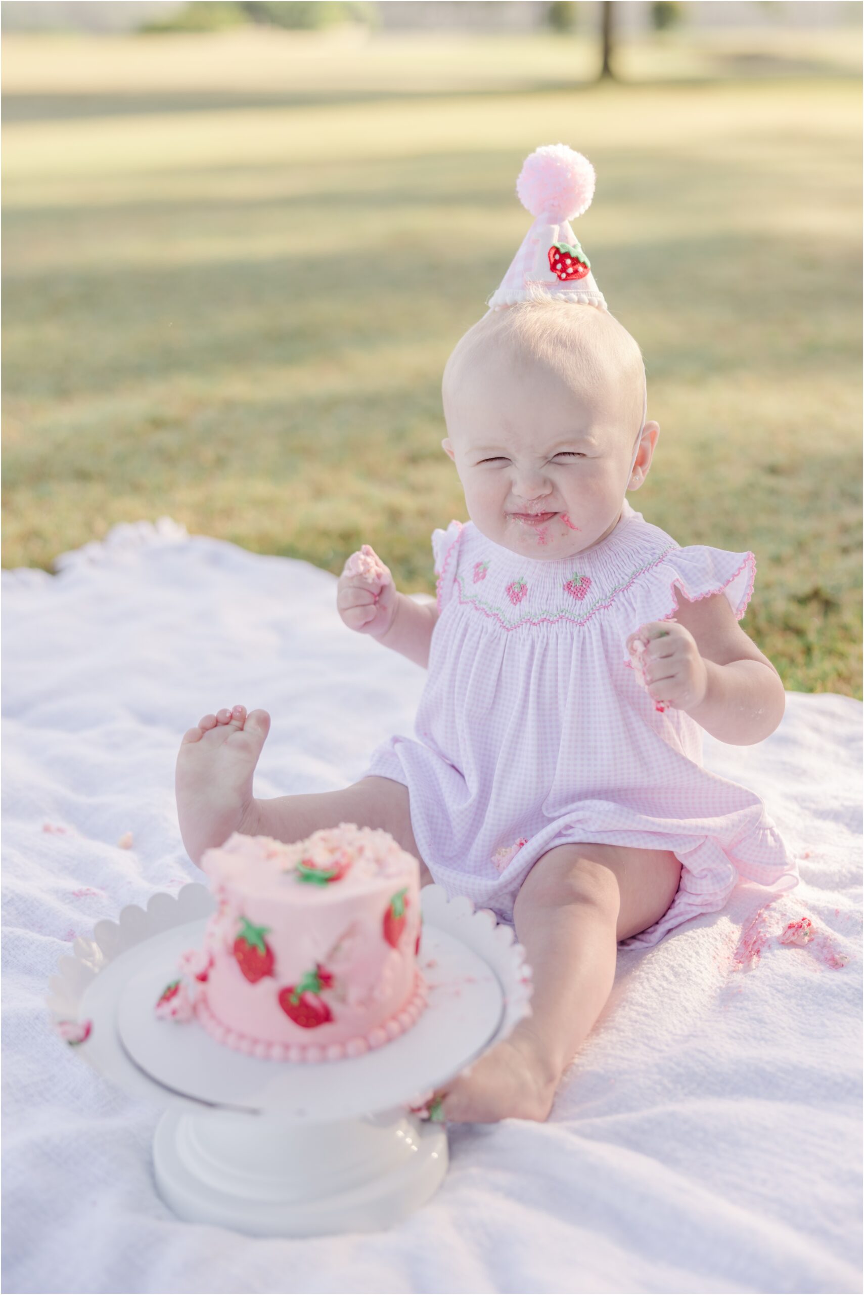 Portrait of a one year old with a strawberry smash cake.