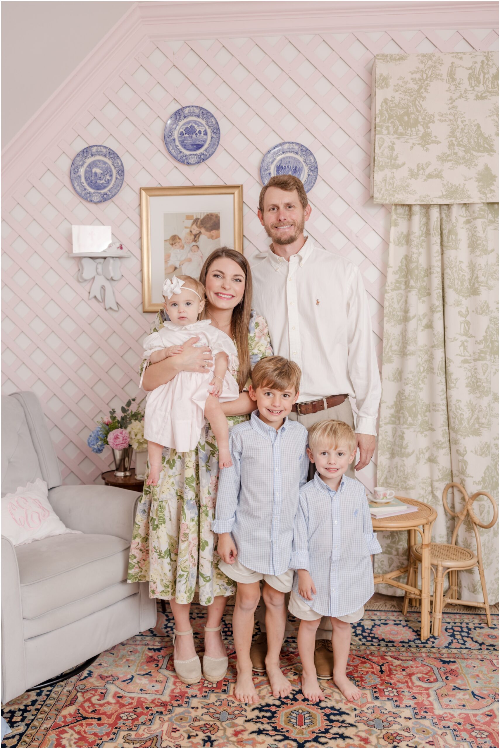 A young family poses in a one year old's Grandmillenial designed nursery furing her Greenville first birthday portratis.