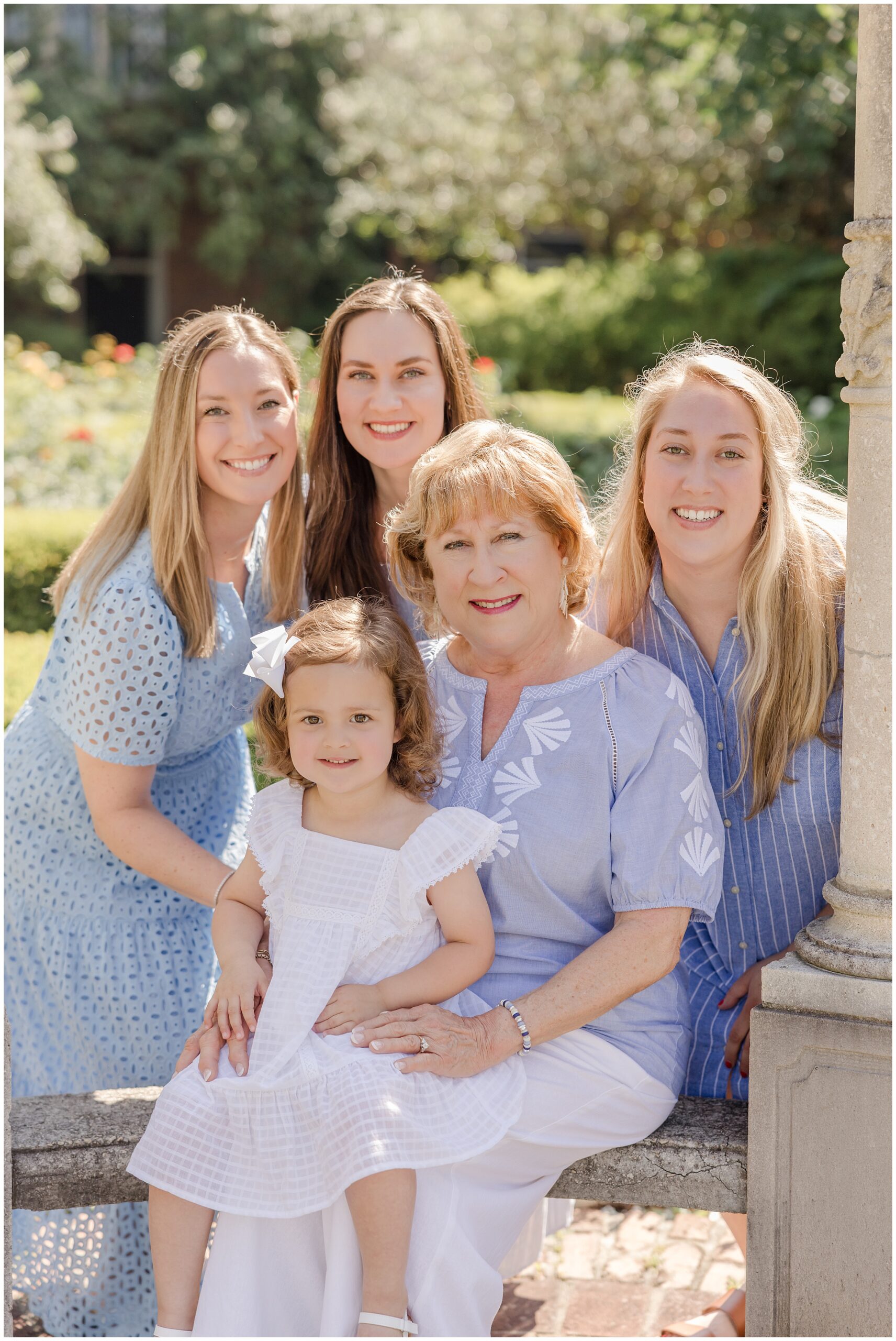 Portrait of a grandmother with her daughters and granddaughter in a garden setting.